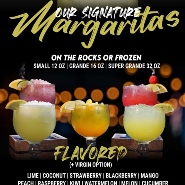 Five colorful margaritas in various flavors and sizes, garnished with fruit, against a dark, bokeh background.