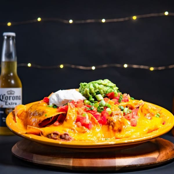 El Mirador 2 nachos with cheese, guacamole, sour cream, tomatoes, and green onions, with a Corona beer.